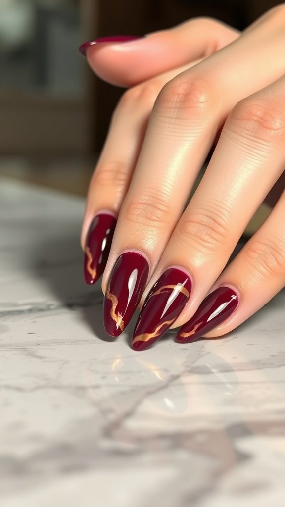 Close-up of cherry wine marble effect nails with gold accents on a marble surface.