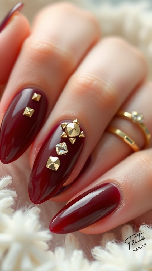 Close-up of cherry wine nails featuring studded details in gold.