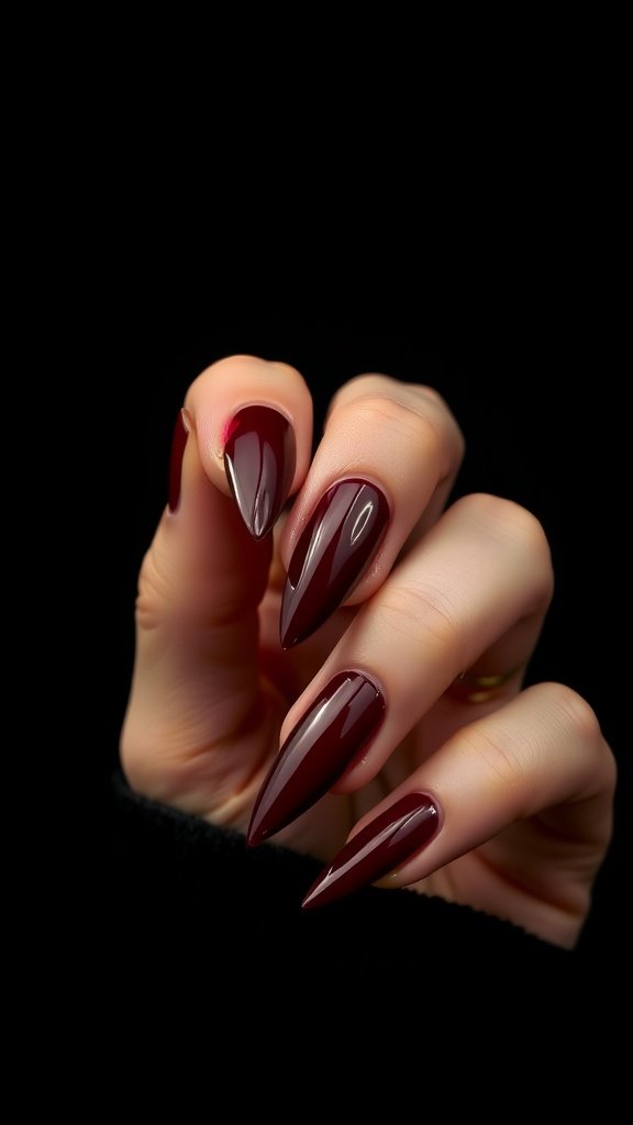 A hand showing cherry wine stiletto nails in a rich red polish against a dark background.