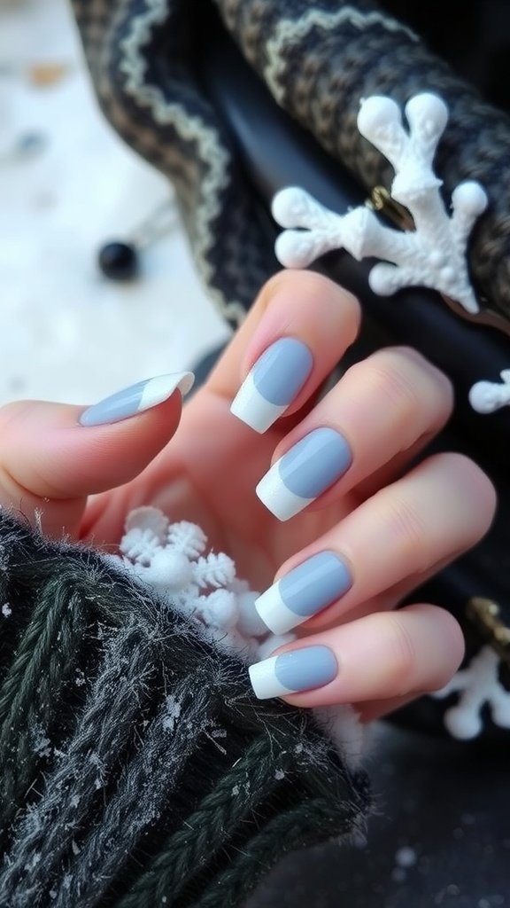 Nails with gray polish and white French tips, resting on a knitted sweater