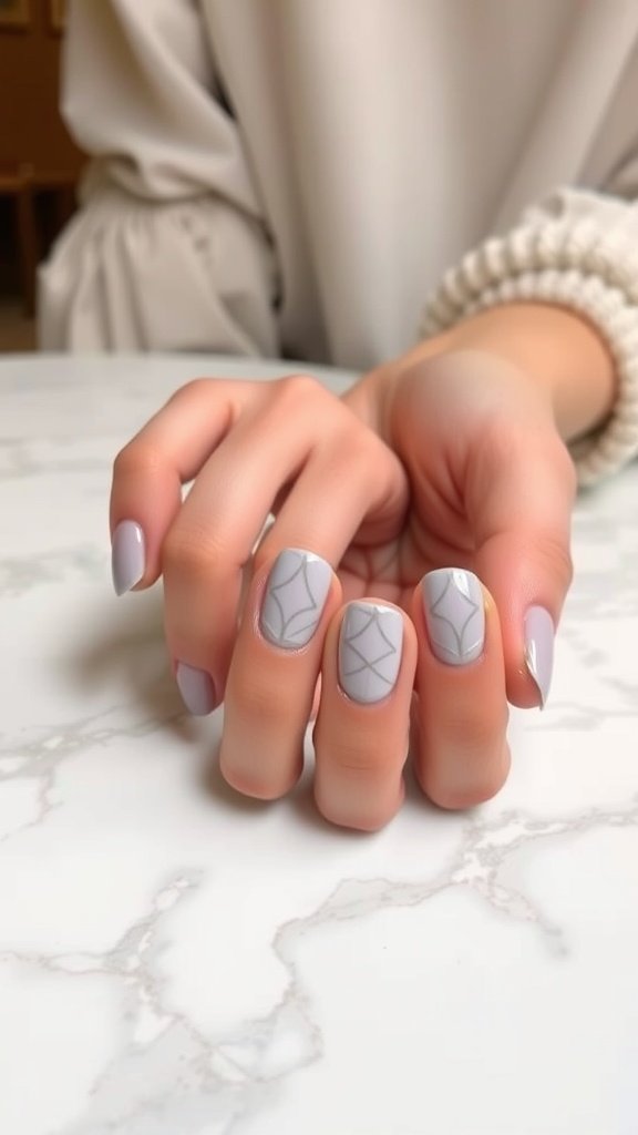 Light grey nails with geometric patterns on a marble table